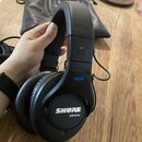 Černé centerXlupovací sluchátka s nápisem SHURE SRH440 na vnější straně mušle. Na horní části náušníku je modrý štítek s nápisem LEFT. Povrch plastov…