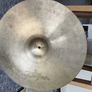 Kruhový mosazný činel s viditelným broušením povrchu. Na pravé straně je vyryto logo Zildjian. Povrch vykazuje drobné škrábance a mírné oxidace.