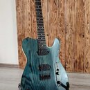 Elektrická kytara s modrým průsvitným lakem a výraznou strukturou dřeva. Nástroj má dva humbuckery, černý hmatník a stříbrný most. Na těle nejsou vid…