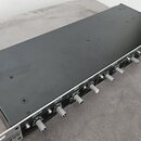 Černý rackový procesor s řadou stříbrných otočných ovladačů na předním panelu. Na panelu jsou vidět nápisy „CHANNEL“, „LOW CUT“ a „GAIN“. Zařízení je…