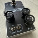 Kytarový efekt pedál v stříbrném kovovém šasi s černým horním panelem. Na panelu je bílý nápis CMOS Bass Overdrive a značka ROTUBE. Zařízení má čtyři…