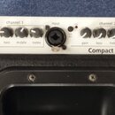 Horní ovládací panel černého komba s bílým podkladem ovladačů. Na panelu jsou nápisy channel 1, input, clip, channel 2, select a power, dále Compact…
