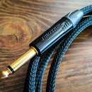 Černý audio kabel s pleteným oplatením a pozlaceným 6,3mm jack konektorem. Na černém plastovém krytu konektoru je vyražen nápis NEUTRIK. Povrch kabel…