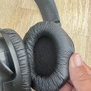Černé centerXlupovací sluchátka s kabelovým připojení. Polstrování náušníků a hlavového oblouku vykazuje výrazné vrásnění a známky opotřebení materiá…