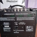 Zadní strana černého kytarového komba s nápisem MODEL: HT-1R. Na zařízení je umístěna velká štítková nálepka se značkou Blackstar, nápisy MAINS INPUT…