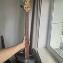 Čtyřstrunná elektrická basová kytara s černým bodies a světle hnědým hmatníkem. Na hlavě je viditelné logo "Squier". Nástroj má dva snímače a čtyři l…