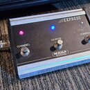 Černý oválný pedál s hliníkovými lištami v horní a spodní části. Na zařízení jsou tři přepínače s nápisy CHANNEL, REVERB a CONTOUR, dvě svítící kontr…