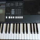 Černý digitální klavír značky YAMAHA, model PSR E423. Nástroj má bílé a černé klávesy a ovládací panel s numerickou klávesnicí, tlačítky pro výběr st…