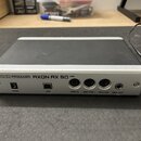 Stříbrně-šedý audio rozhraní s matným povrchem. Na přední straně jsou nápisy TERRATEC PRODUCER AXON AX 50 USB a označení konektorů 12VAC, USB, MIDI I…
