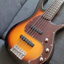 Pětstrunová elektrická basová kytara s korpusem v přechodovém lakování od černé přes oranžovou k žluté. Nástroj má červeně mramorovaný pickguard a dv…