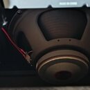 Fotografie zachycuje zadní část černého reproduktoru s viditelným magnetem. K reproduktoru vedou červený a černý elektrický vodič. V horní části je v…
