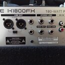 Záběr na zadní panel stříbrného zesilovače s nápisy TONE K1800FX a 180-WATT PA/KEYE. Jsou zde vidět konektory LINE OUT (L a R BALANCED), STEREO LINK…
