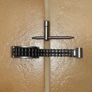 Fotografie zobrazuje kovové příslušenství v stříbrné barvě položené na béžovém povrchu. Nahoře je T-klíč s rýhovanou rukojetí a šroubovákem. Dole se…