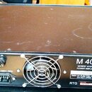 Zadní strana černého rackového zesilovače s chladicími žebry po stranách. Na přístroji jsou nápisy M 400, MOSFET STEREO POWER AMPLIFIER a Serial No.…