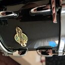 Detail černého bubnu s chromovaným obručováním a lugy. Na korpusu je viditelný štít s nápisy „Pearl“, „Masters“ a „PREMIUM MAPLE“. Na chromovaném obr…