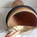 Fotografie zachycuje pohled do vnitřku dřevěného bubnu s kůží. Okraj nástroje je opleten černým provázkem a spodní část kůže vykazuje přirozené zbarv…