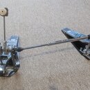 Dvojpedál na bicí v kovovém provedení s černými plošinkami. Na levé plošince je vidět nápis "THE LEGEND" a "INNOVATION". Mechanismus vykazuje známky…