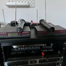 Černý rack s dvěma bezdrátovými přijímači značky SENNHEISER a nápisem TRUE DIVERSITY RECEIVER G910. Na接收ačích leží dva černé bezdrátové mikrofony, z…
