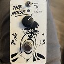 Bílý efekt pedál s černým grafickým motivem křičící tváře. Na horní části je nápis THE NOISE a přepínač s označením HARD (vyznačené plnou hvězdou) a…