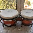 Sada dvou kongů v oranžové barvě s černými obručemi a kovovým hardwarem. Na blanách i na spodní části korpusů je vidět logo a nápis Matador Custom. P…