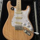 Elektrická kytara s přírodním dřevěným povrchem těla a hmatníkem z jasnu. Nástroj má bílý perleťový pickguard, tři snímače s krémovými kryty a chromo…