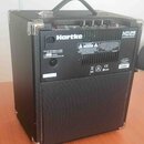 Černý basový kombozesilovač s kovovými hranami a přenosnou rukojetí. Na zadním panelu je bílý nápis Hartke a modelové označení HD25 25 WATT BASS AMPL…