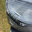 Detailní pohled na chromovaný obruč bubnu, který je zabalen v průhledné fólii a bublinkové fólii. Na horní straně je vidět napnutá blána s šedým text…