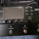 Černý kytarový procesor Fractal Audio Systems VP4 Virtual Pedalboard. Zařízení má digitální displej, pět ovládacích tlačítek s nápisy HOME, SAVE, PAG…