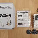 Bílé zařízení Two notes AUDIO ENGINEERING s nápisem Torpedo C.A.B. M a digitálním displejem. Vedle něj je bílá krabice s logem Two notes AUDIO ENGINE…