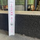 Detailní záběr na černý, hrubě strukturovaný povrch materiálu. Vedle něj je přiložen bílý skladací metr značky STABILA s červenými a černými číslicem…