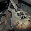 Elektrická kytara s tmavě hnědým matným povrchem a výraznou dřevěnou strukturou na topu. Nástroj má dva černá humbuckery, stříbrný kobylník a jeden o…