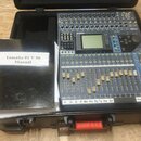Digitální mixážní pult Yamaha 01V96 umístěný v černém transportním kufru. Zařízení má modrošedé provedení s řadou posuvníků, tlačítek a centrálním di…