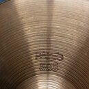 Detailní pohled na povrch mosazného činele s koncentrickým broušením. Na povrchu jsou vyraženy nápisy PAISTE a 505, přičemž horní nápis je méně výraz…
