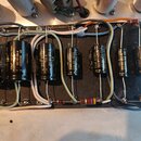 Fotografie zachycuje vnitřní elektronický zapojení s řadou černých elektrolytických kondenzátorů na černé desce. Na kondenzátorech jsou nápisy 220µF…