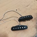 Dvě elektrické kytarové snímače v černé barvě s černými plastovými kryty. Horní snímač je typu humbucker se dvěmi řadami magnetů, spodní je jednoduch…