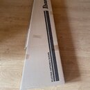 Kartonový obal v hnědé barvě určený pro hudební nástroj. Na povrchu je černý nápis Ibanez a text ELECTRIC GUITARS & BASSES. Krabice vykazuje známky o…