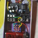 Fotografie zachycuje vnitřek efektpedálu v kovovém fialovém šasi. Uvnitř je umístěna elektronika na černém plošnicovém desce s různými součástkami, d…