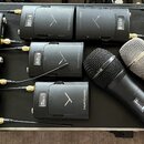 Sada devíti černých bezdrátových vysílačů s nápisem beyerdynamic a logem ve tvaru písmene V. Zařízení jsou umístěna na černém povrchu, z některých ve…