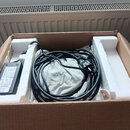 V kartonové krabici s polystyrenovými vložkami je černý síťový adaptér a smotaný černý kabel. Na štítku adaptéru je vidět nápis Roland a označení AC-…