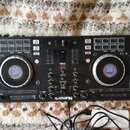 Černý DJ kontrolér značky Numark s modelem MixTrack Platinum. Zařízení má dva velké jog-kola s digitálními displeji v centru a centrální mixážní sekc…