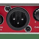 Detailní pohled na přední panel stříbrného elektronického zařízení s červeným prostředním panelem. Jsou zde vidět vstupy a ovládací prvky s nápisy IN…