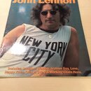 Fotografie znázorňuje zpěvník s nápisem The Great Songs of John Lennon a nadpisem Piano/Vocal/Guitar. Na obálce je vyobrazen muž v slunečních brýleh…
