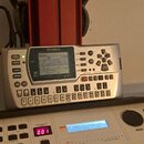 Stříbrný digitální sequencer značky YAMAHA, model PSR-100. Zařízení má LCD displej a řadu ovládacích tlačítek s nápisy jako SONG, PATTERN, ENTER či E…