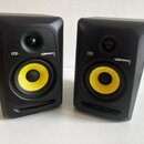 Dva černé studiové monitory s žlutými membránami basových reproduktorů. Na obou je vidět logo KRK a nápis ROKIT 5. Povrch krytů vykazuje drobné nečis…