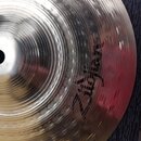 Detailní pohled na kovový činel stříbrné barvy s výrazným kovánívým povrchem. Na povrchu je černý nápis Zildjian a v horní části text MADE IN THE USA…