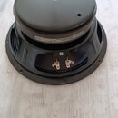 Fotografie znázorňuje zadní část reproduktorového hovorníku v černé barvě. Na magnetu je viditelný bílý štítek s nápisy „Made in USA by Eminence“, „a…