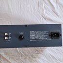 Fotografie zachycuje zadní část šedého elektronického zařízení. Jsou zde vidět konektory s popisky UNBAL IN, UNBAL OUT a BAL/UNBAL OUTPUT, vlevo dole…