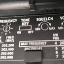 Detailní pohled na ovládací panel černého elektronického zařízení. Jsou zde vidět nápisy FREQUENCY, TONE KEY s přepínačem ON/OFF, SQUELCH a VOLUME s…