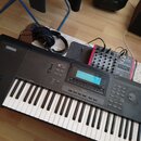 Černý digitální klavír s bílými a černými klávesami, v levém horním rohu je bílý nápis YAMAHA. Nástroj má ovládací panel s displejem, tlačítky a voli…