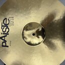 Zlatý kovový činel s koncentrickým žebrováním povrchu. Na povrchu je černý nápis pAiste, nad kterým je svisle napsáno BRASS a vedle něj číslo 101, v…